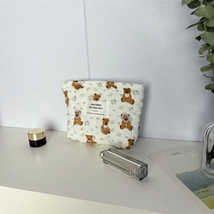 Détail de la texture matelassée et imprimé ours sur la grande trousse à maquillage beige
