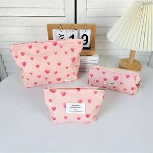 Three-piece set of pink canvas makeup bags with red heart patterns and zipper closures