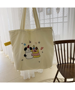 Close-up of beige canvas tote bag featuring cute cartoon towel embroidery and drawstrings