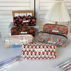 Floral corduroy pencil case assortment with vintage prints and zip closure on a desk
