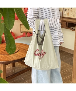 Detail of light green checkered nylon tote bag with red Candy lettering on wide strap