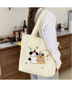 Detail of cute towel-embroidered cartoon dog pattern on a cream canvas tote bag