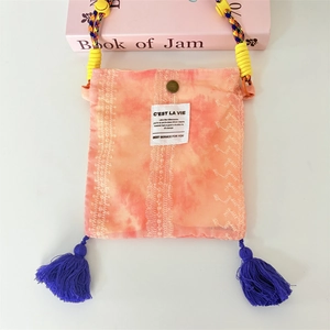 Detail view of tie-dye crossbody bag featuring embroidery, metal buckle and purple tassels