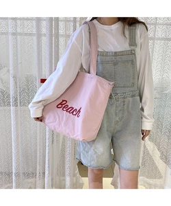 Detailed close-up of pink nylon tote bag featuring red Beach embroidery and drawstrings
