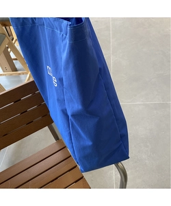 Detail view of durable blue canvas tote bag showing white letter print and fabric texture