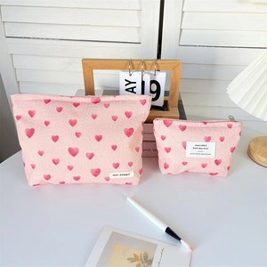 Detail shot of pink heart-patterned canvas toiletry bags with textured fabric and zippers