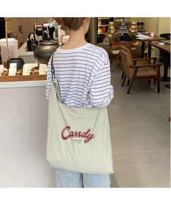 Detail view of large green checkered nylon tote bag with red Candy text on a model