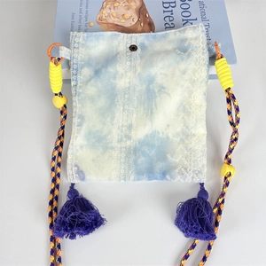 Detail of bohemian tie-dye crossbody bag with lace embroidery and purple tassel accents