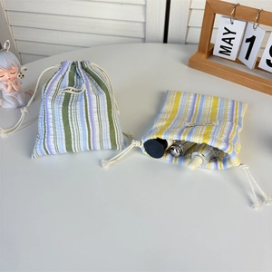 Détail de pochettes rayées à cordon montrant le tissu texturé pour les cosmétiques