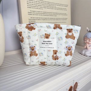 Détail de la trousse matelassée en coton avec motif d'ours et étiquette tissée de marque