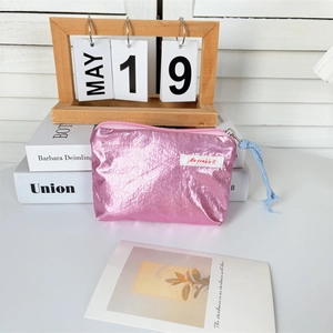 Detail of metallic pink coin purse with wrinkled texture and blue knot zipper pull