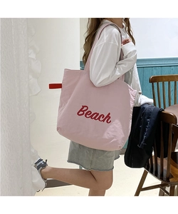Detailed view of pink nylon tote bag with red Beach lettering and functional side loop