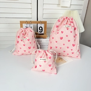 Detailed view of pink drawstring storage bags set with heart patterns in three sizes
