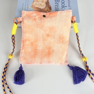 Detail of bohemian tie-dye crossbody bag with lace stripes and purple tassels