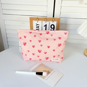 Detailed close-up of pink heart pattern canvas makeup bag with metallic zipper and label