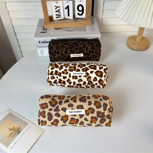 Three leopard print corduroy pencil cases in brown and beige tones on a desk