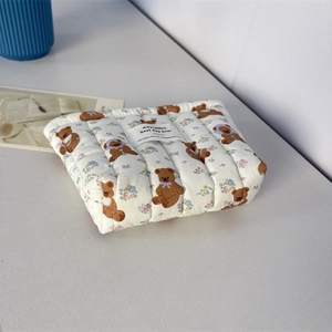 Détail latéral d'une trousse à maquillage matelassée avec motifs ours et fleurs