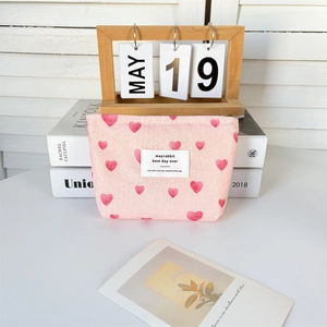 Detailed close-up of pink heart-printed canvas makeup bag with top zipper and label