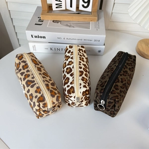 Close-up of three corduroy leopard print pouches with stylish silver circular metal zippers