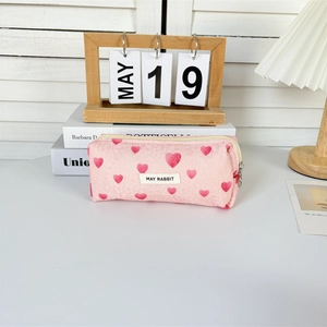 Detailed close-up of pink heart jacquard fabric with embroidered brand label and zipper
