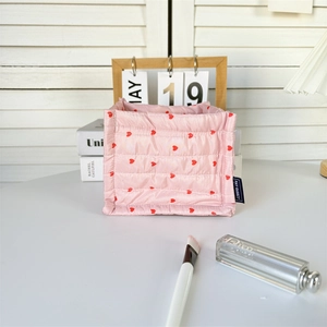Close-up of pink quilted storage basket with red heart patterns and brand fabric label