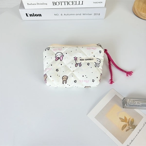 Dettaglio di mini pochette trapuntata con motivi a coniglio, zip con cordino rosa ed etichetta