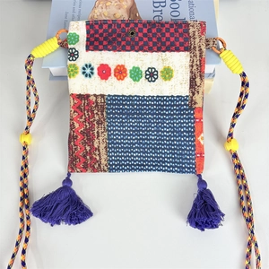 Close-up of bohemian plaid fabric crossbody bag with floral embroidery and blue tassels