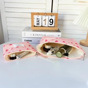 Detail of pink heart-pattern canvas cosmetic bags in large and small sizes with silver zippers