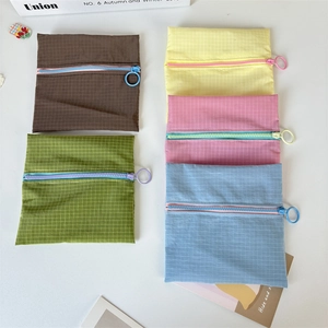 Flat lay of five colorful nylon mini zipper pouches with large pull rings and grid pattern
