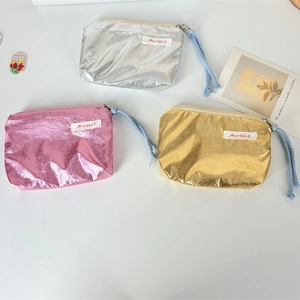 Detail view of sparkly metallic makeup bags in silver, pink, and gold with rope zippers