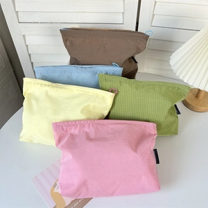 Detail of colorful plaid nylon toiletry bags with smooth circular zipper pulls and brand labels
