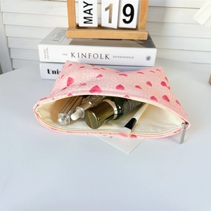 Pink heart canvas makeup bag with spacious interior holding lipsticks and skincare bottles
