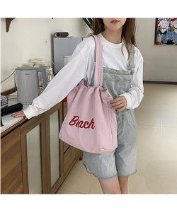 Pink nylon drawstring tote bag with red Beach lettering detail and shoulder strap