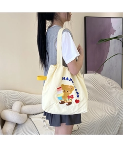 Detail of cartoon bear embroidery and blue HAPPINESS lettering on canvas tote