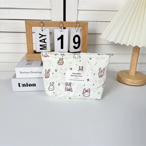 Detail of white quilted cosmetic bag featuring cute rabbit patterns and a zipper closure