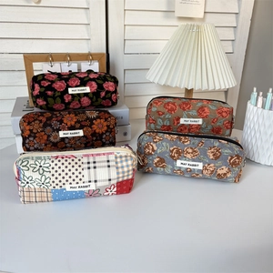 Various corduroy floral pouches displayed with a vintage lamp and wooden decor