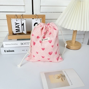 Detailed view of pink drawstring bag with heart patterns and textured lace fabric