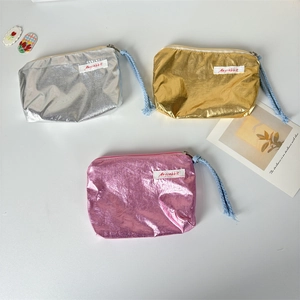 Close-up of metallic finish coin purses in gold, silver and pink with fabric labels
