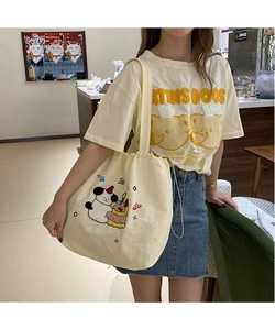 Detail of cream canvas drawstring tote bag with embroidered cartoon animal and cake