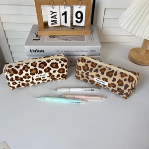 Close-up of leopard print corduroy pencil cases with a brand tag and zipper closure