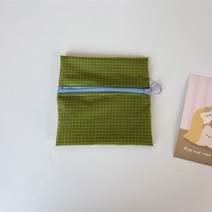 Detail view of green checkered nylon coin purse with contrast colorful zipper and ring pull