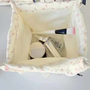 Top view of floral quilted storage basket showing spacious interior with cosmetic bottles