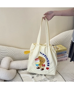 Detail of cream canvas tote bag featuring bear embroidery and drawstring closure