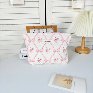 Détail d'une trousse à maquillage matelassée en coton avec motifs roses et fermeture éclair