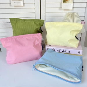 Waterproof nylon grid cosmetic bags in four pastel colors on a bright minimalist desk