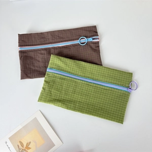 Close-up of minimalist checkered nylon pouches with colorful ring-pull zippers