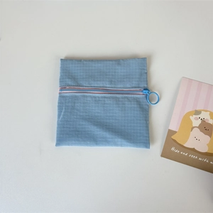 Detail of blue grid nylon coin purse featuring a large circular ring zipper puller