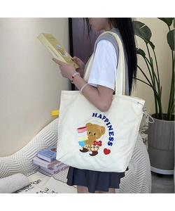 Close-up of happiness bear embroidery on a cream canvas tote bag with side drawstring