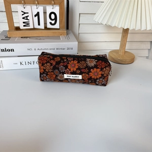 Close-up of vintage corduroy floral pencil case on desk with cozy aesthetic decor