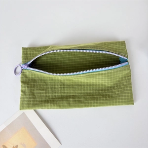 Detail of green nylon bag with purple zipper showing inner storage and grid pattern